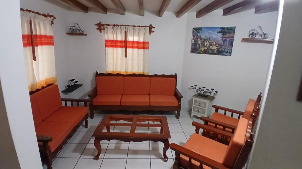 a living room with orange couches and a coffee table at Posada "CASA BONITA" in La Cal