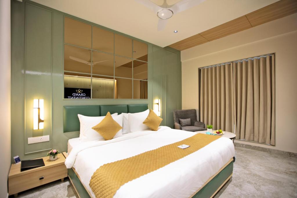 a bedroom with a large bed and a chair at Grand Continent Dwarka in Dwarka