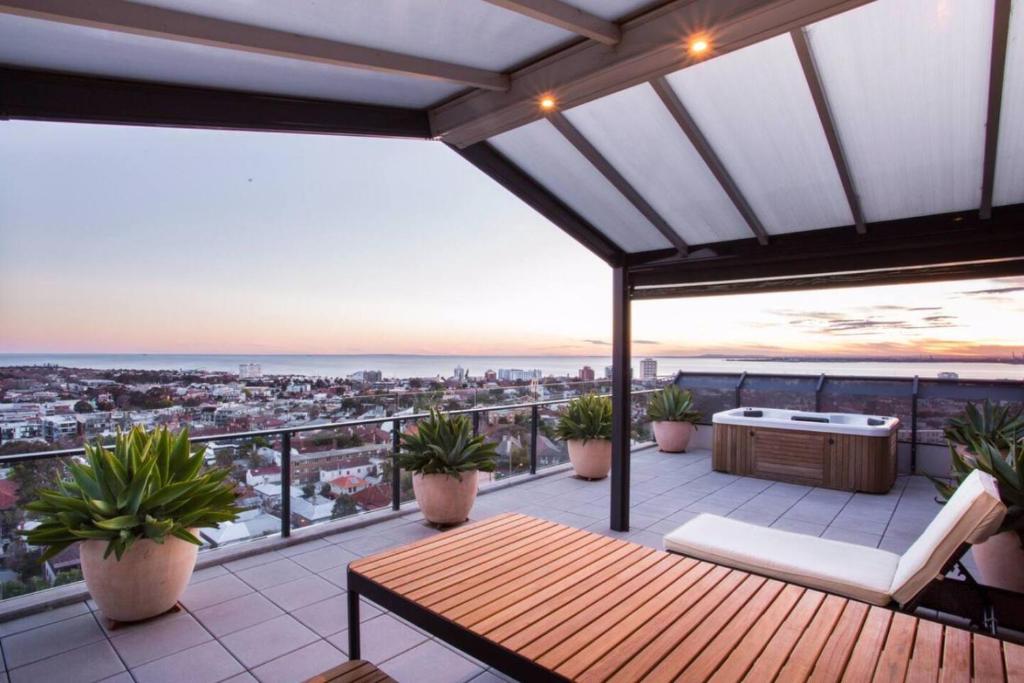 un patio en la azotea con una mesa y macetas en St Kilda Penthouse. Views. Spa., en Melbourne