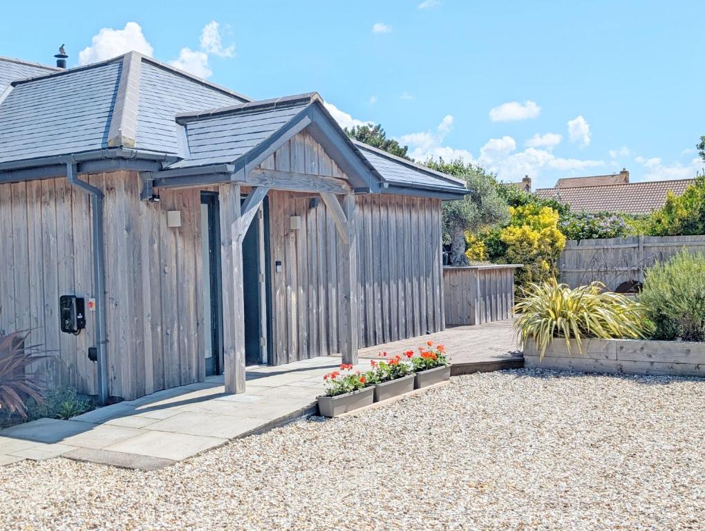 une cabane en bois avec une clôture dans un jardin dans l'établissement The Salt Shack - Bracklesham, à East Wittering