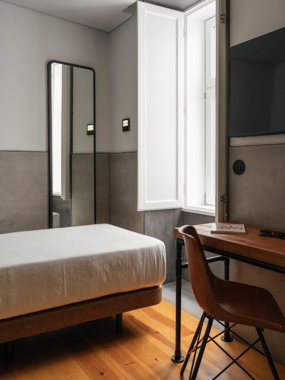 A bedroom workspace beside a window, with a desk, chair and wall-mounted television.