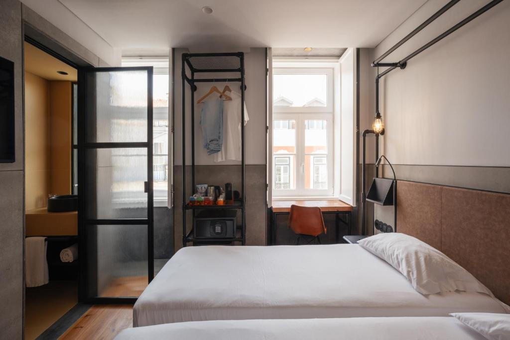 A compact double bedroom with a window-facing desk and open clothes rack.