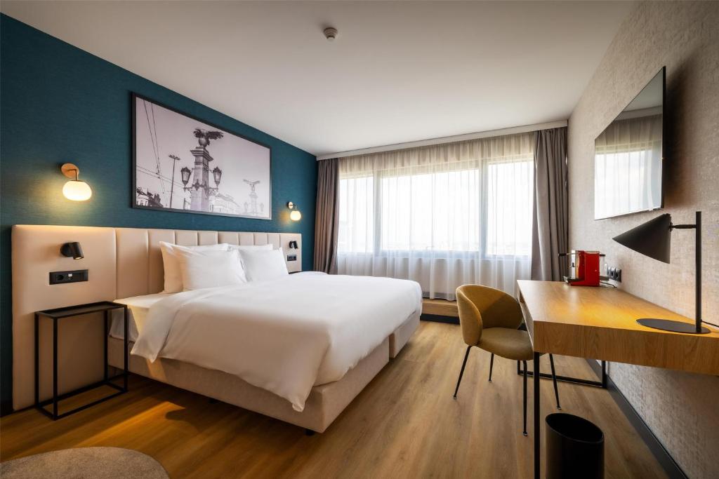 ein Hotelzimmer mit einem großen Bett und einem Schreibtisch in der Unterkunft Metropolitan Hotel Sofia, a member of Radisson Individuals in Sofia