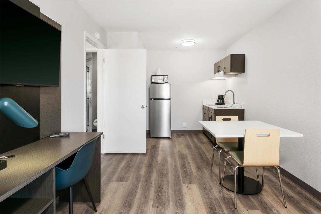 a kitchen with a table and chairs and a refrigerator at Studio 6 Tempe, AZ Elliot Road in Tempe