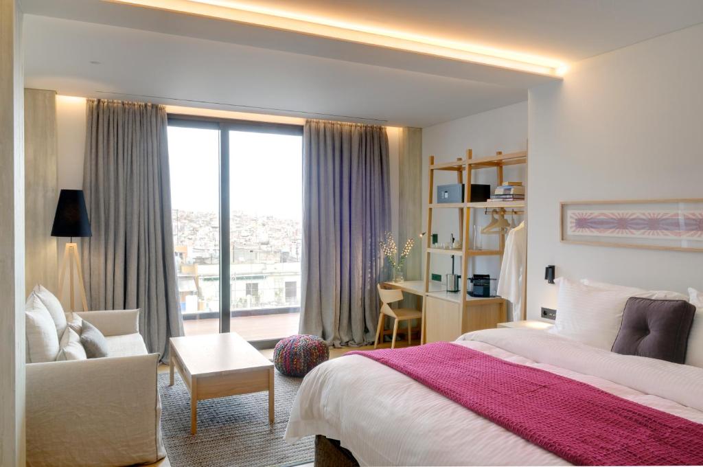 a bedroom with a bed and a chair and a window at Coco-Mat Hotel Athens in Athens