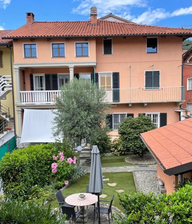 a house with a table and an umbrella in the yard at Camelia Casa Vacanze in Palazzo Canavese