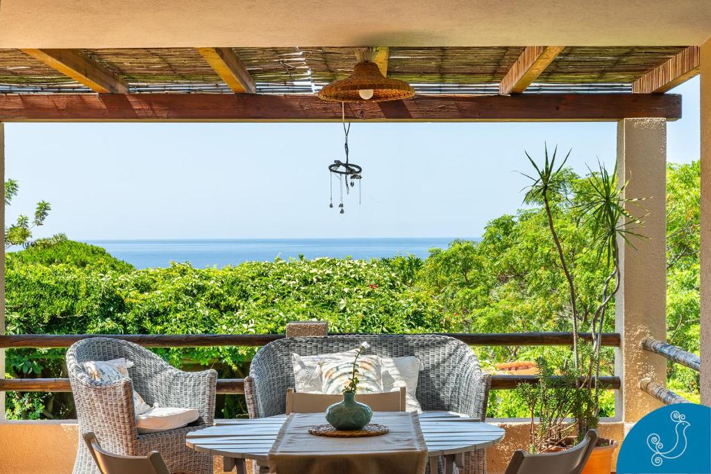 a patio with a table and chairs and the ocean at La Bouganville - House with garden and sea view in Geremèas