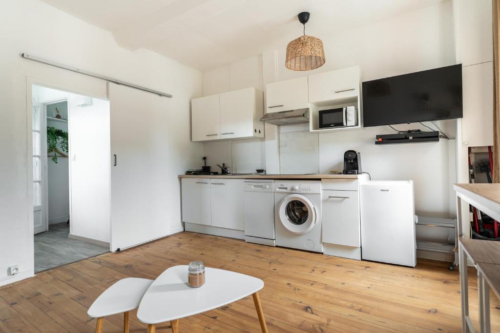 a kitchen with white cabinets and a washer and dryer at Barrière naturelle in Toulouse
