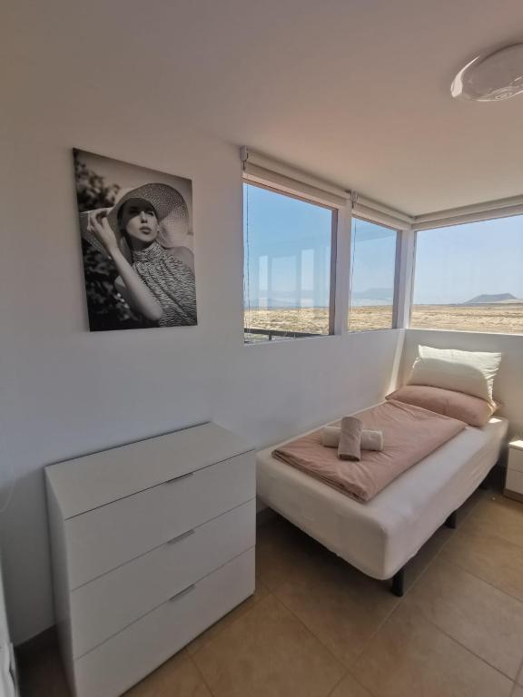 1 dormitorio con 1 cama con vestidor y ventanas en Villa Sol Naciente, en Lajares