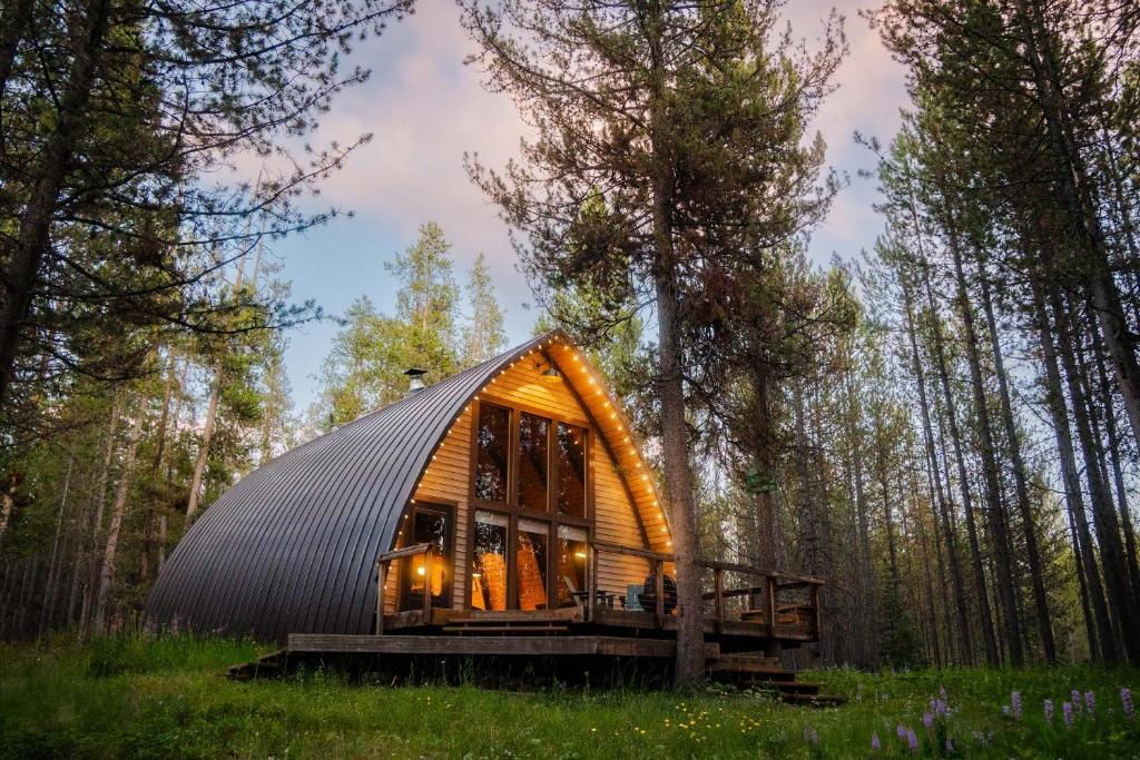 a round cabin in the woods with a black roof at A Frame Hot Tub Couple's Getaway in Island Park