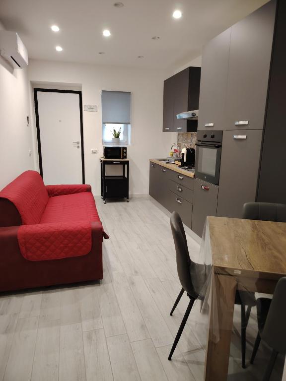 a living room with a red couch and a kitchen at La Casetta di Nonno Settimo in Palermo