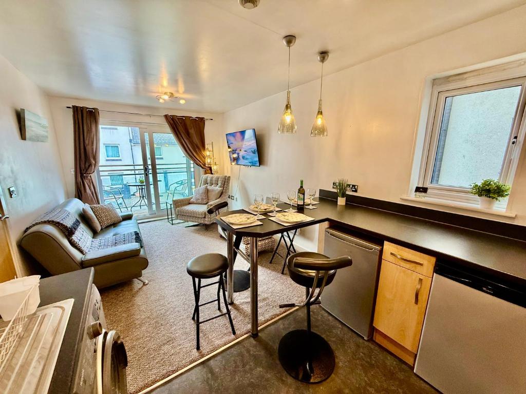 Bon-y-maenにあるCharming River Nest Near the Stadium and City Centre Comfort for Up to 4 Guestsのテーブルと椅子のあるキッチンとリビングルーム