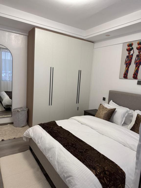 1 dormitorio con 1 cama grande y armarios blancos en City homes, en Nairobi