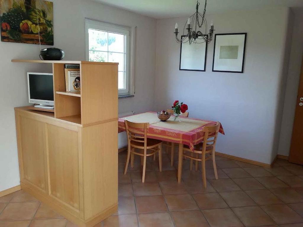a dining room with a table and chairs and a television at Weingut Wissler - Brennerei in Au