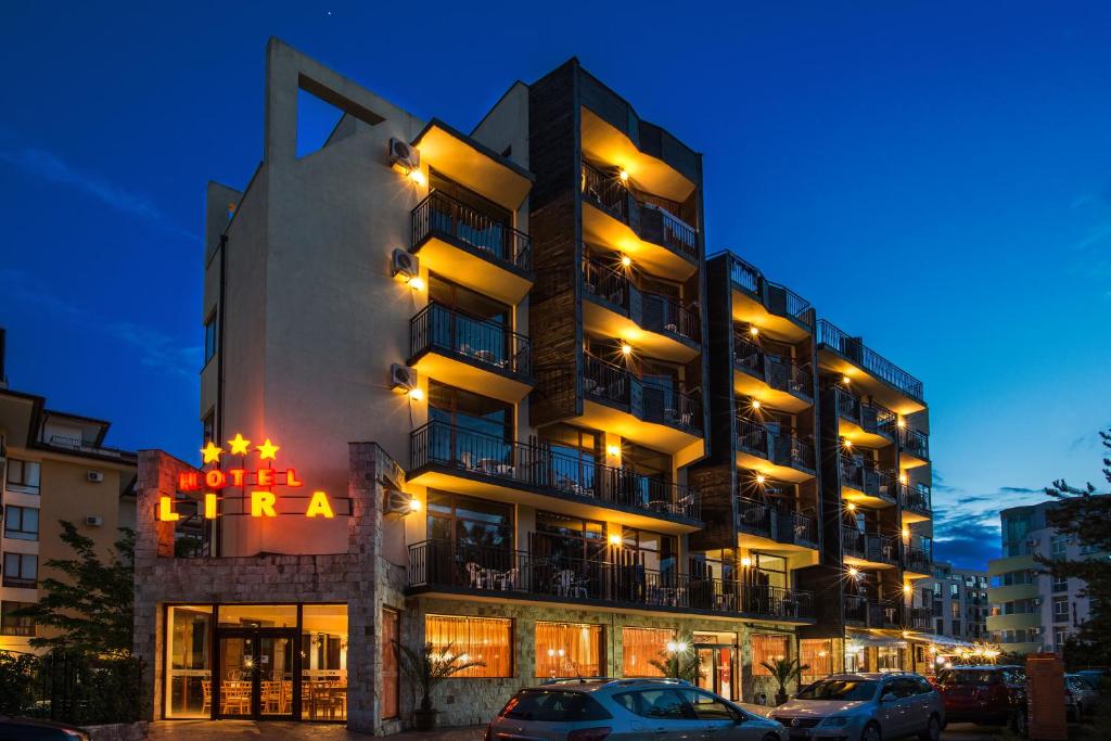 a hotel building with cars parked in front of it at Hotel Lira in Sunny Beach