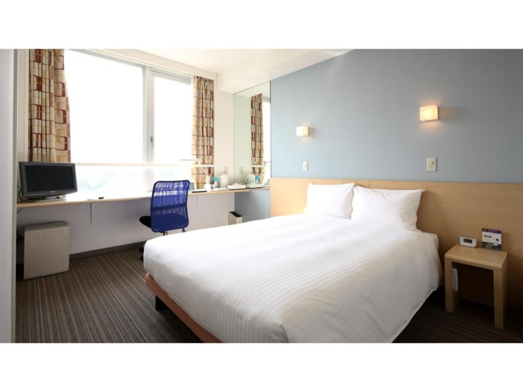 una camera d'albergo con un grande letto bianco e una scrivania di Smile Hotel Sendai Tagajyo - Vacation STAY 84220v a Tagajo