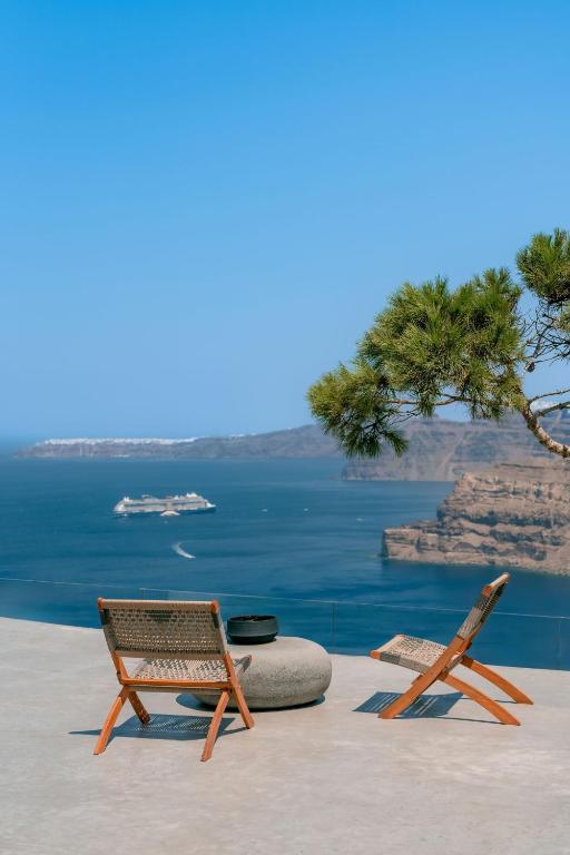 two chairs sitting on a ledge next to the water at Nelya Suites in Megalochori