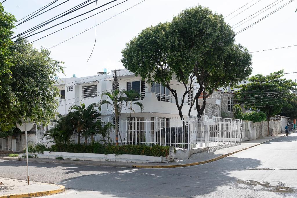 a white house with a fence and trees in front of it at edificio Alba in Cartagena de Indias