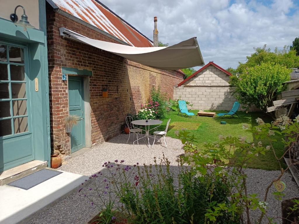 a garden with a patio with a table and a building at Maison De Vacances 