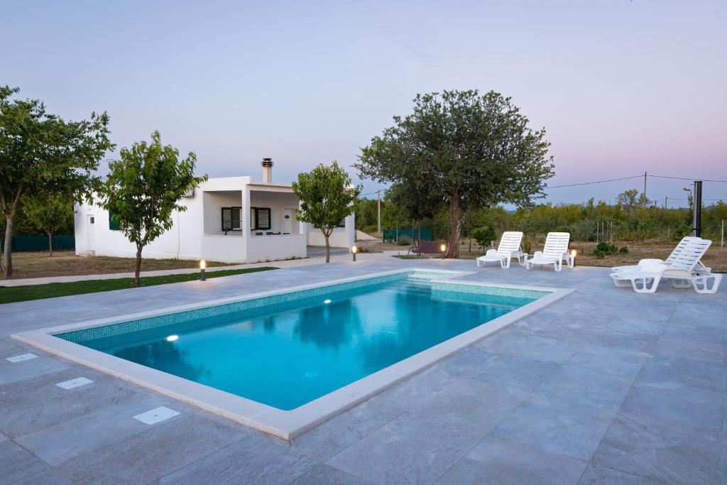 a swimming pool with chairs and a house at Kuća za odmor Matetić in Unešić