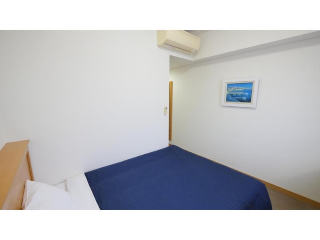 a small room with a blue bed in it at Smile Hotel Shizuoka Yoshida Inter - Vacation STAY 90891v 