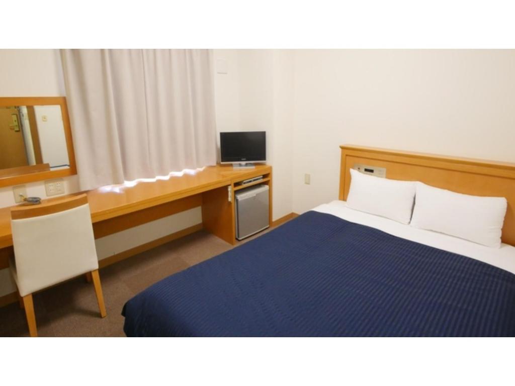 a bedroom with a bed and a desk with a television at Smile Hotel Shizuoka Yoshida Inter - Vacation STAY 90911v 