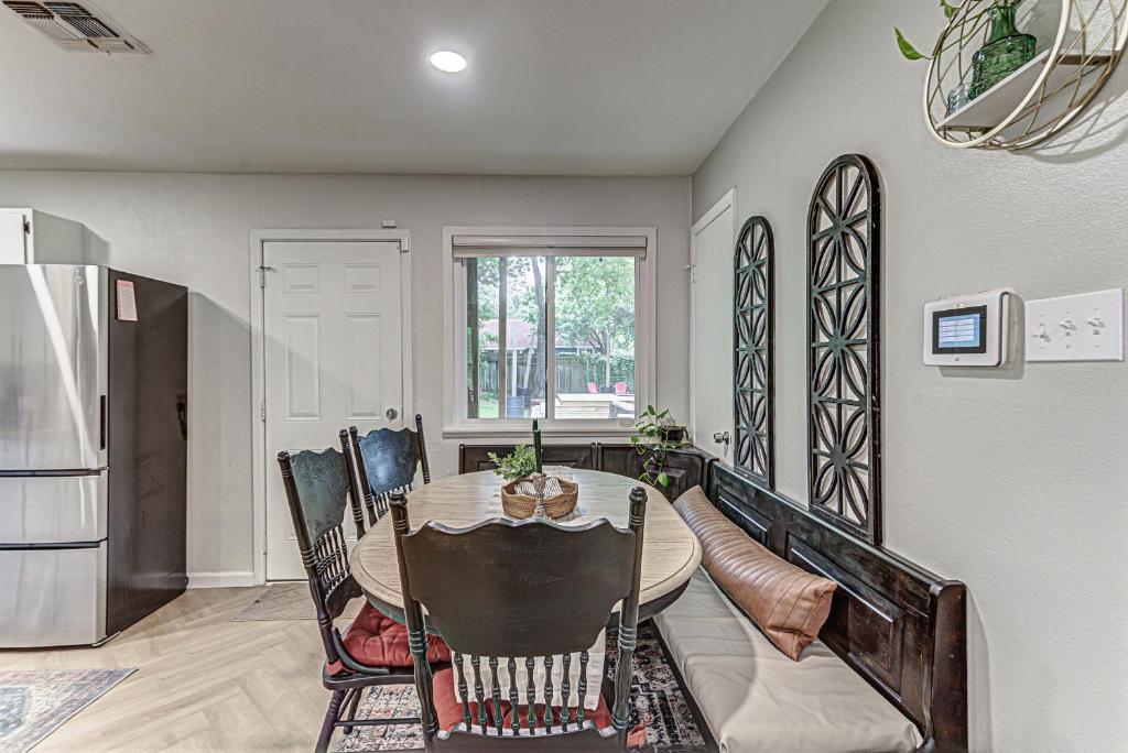 a dining room with a table and chairs and a refrigerator at Dulwich Drift - Cowboy Pool Fire Pit & Chill Backyard Vibes in Austin