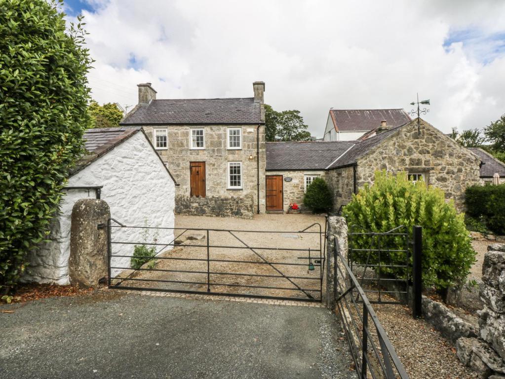an old house with a gate in front of it at Tyddyn Iolyn in Benllech