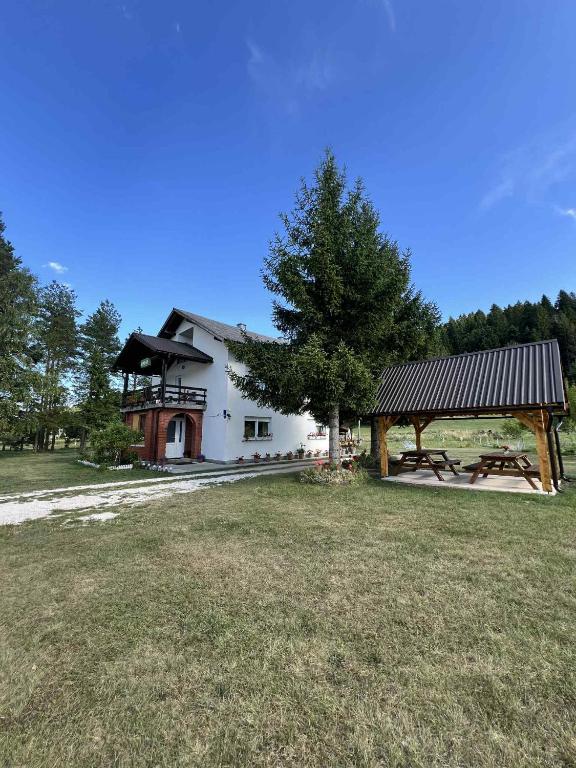 a large white building with a tree and a pavilion at Rooms Danica in Donji Babin Potok