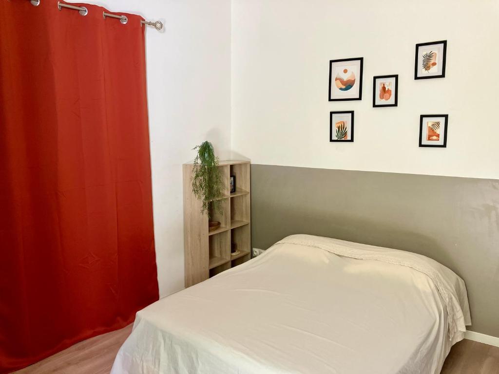 une chambre avec un lit et un rideau rouge dans l'établissement Studio écusson Nîmois et cour ensoleillée, à Nîmes