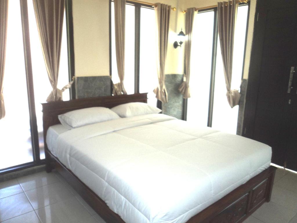 1 dormitorio con 1 cama blanca grande y ventanas en Villa Green House en Nusa Penida