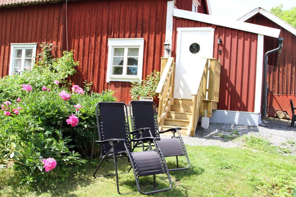 duas cadeiras sentadas em frente a um edifício vermelho em Kolmårdstorpet Blomsätter em Kolmården