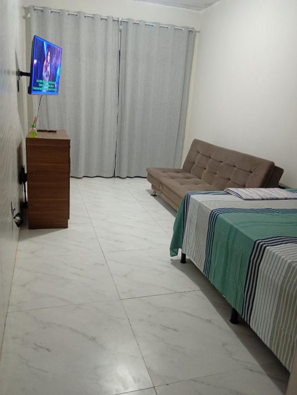a living room with a couch and a flat screen tv at Kitnet temporada in Cabo Frio