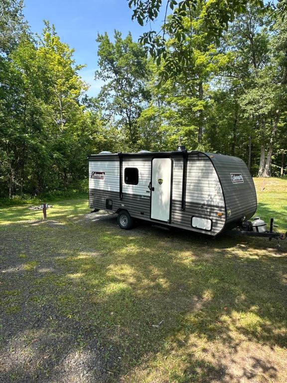 a trailer parked in a field in a forest at Cozy Camper Retreat on Sleepy Hollow Lake in Athens