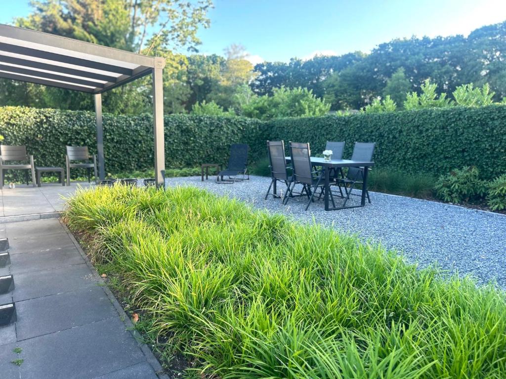 a patio with a table and chairs in a garden at Bosparel met ruime tuin en airco! in Oisterwijk