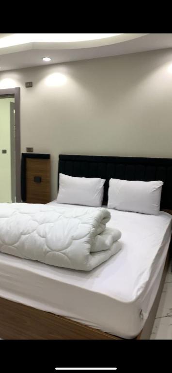 a large white bed with white sheets and pillows at المهندسين in Cairo