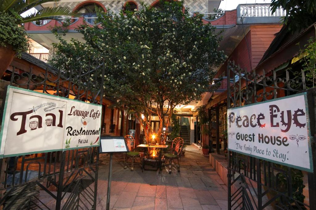 a patio with a table and chairs and signs at Peace Eye Guest House in Pokhara