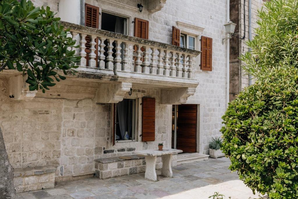 Un edificio de piedra con un balcón y un banco. en Villa Carmen, en Kotor