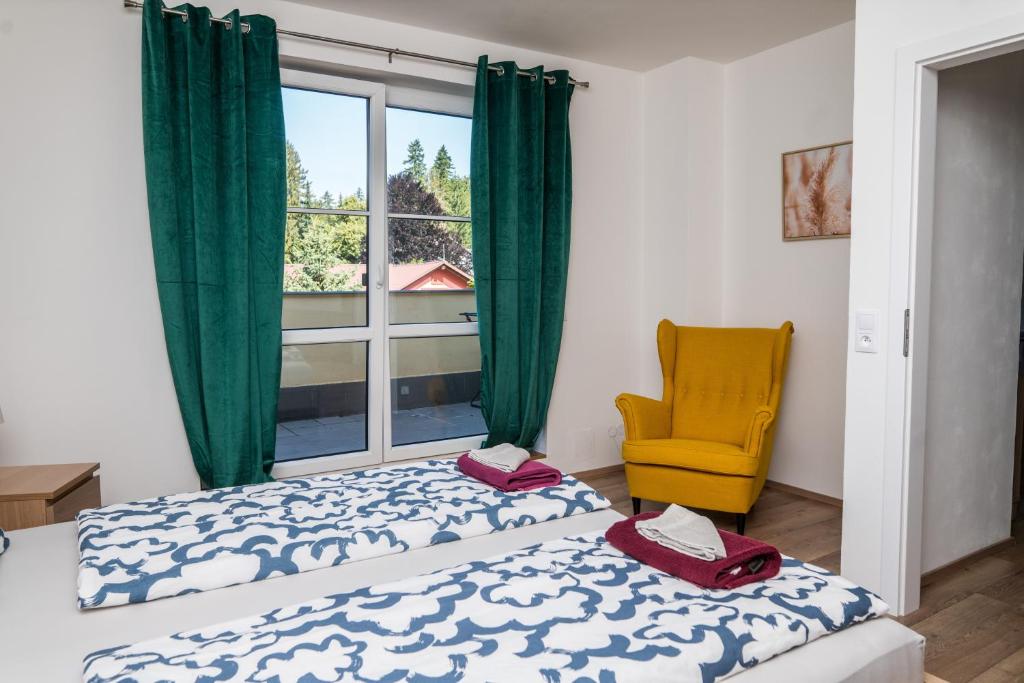 a bedroom with a bed and a window and a yellow chair at Apartmá Kateřina Velké Losiny in Velké Losiny