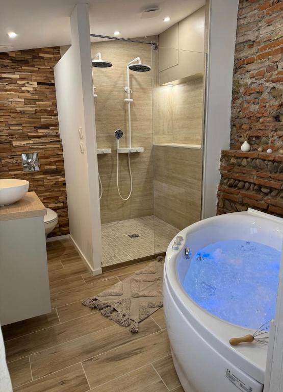 La salle de bains est pourvue d'une grande baignoire et d'une douche. dans l'établissement Escapade Tournefeuille, jacuzzi, balnéo, terrasse, à Tournefeuille