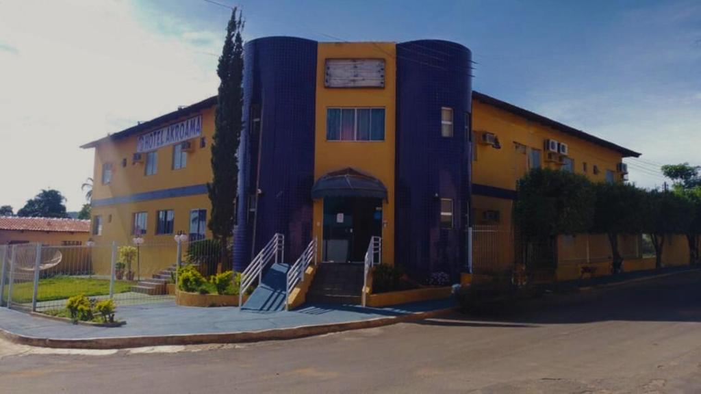 a large yellow and blue building with a porch at Hotel Akroama in Corumbaíba