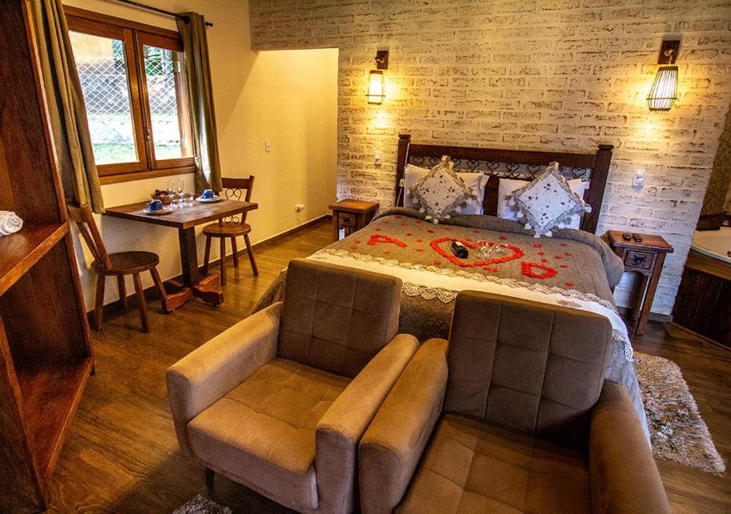a bedroom with a bed and a couch and a table at Chalés Montanha Serrana - Monte Verde in Monte Verde