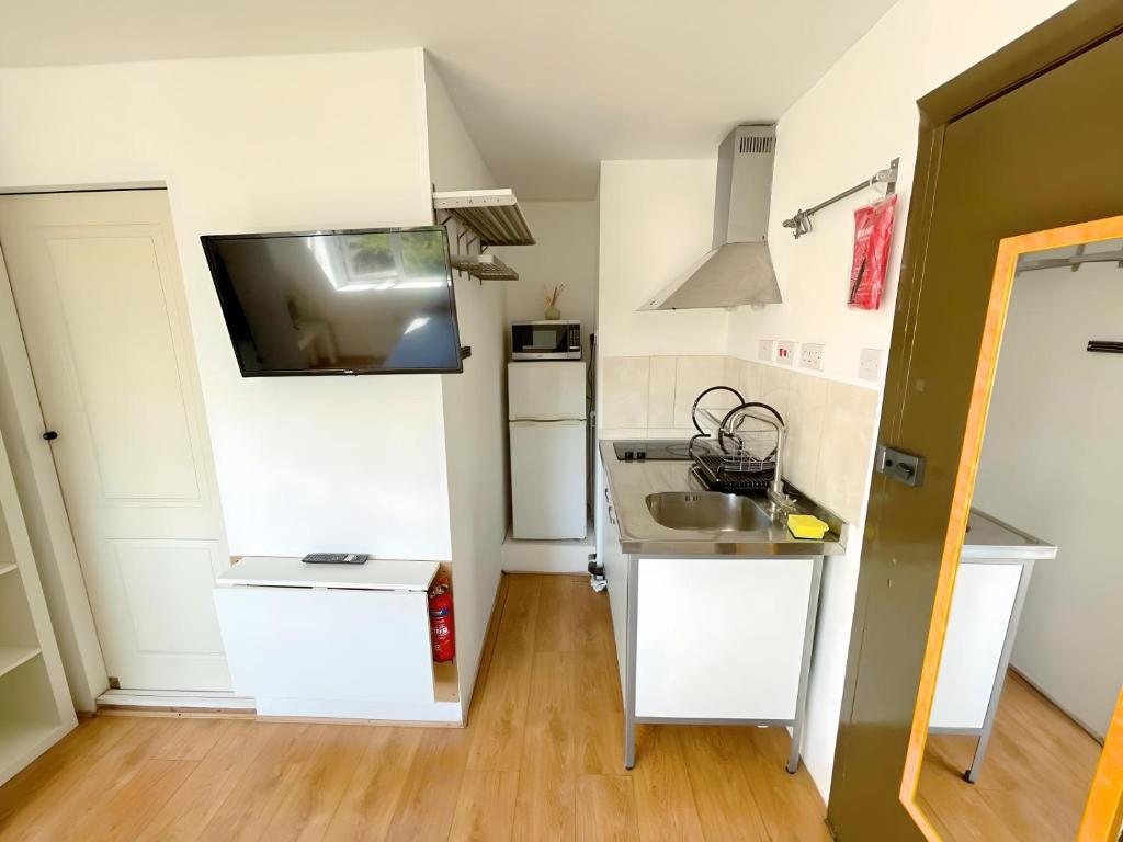a small kitchen with white cabinets and a sink at Bright studio in Excellent location in London