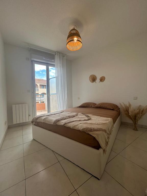 une chambre avec un grand lit et une grande fenêtre dans l'établissement Appartement frejus, à Fréjus