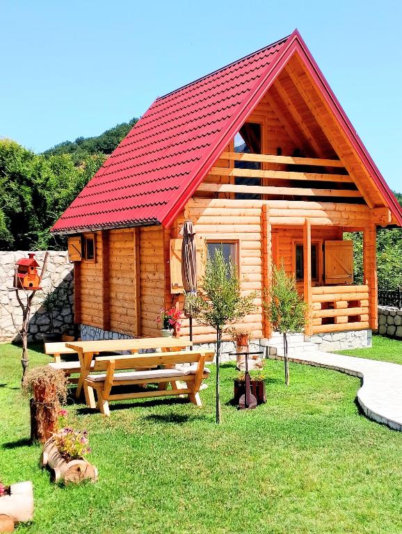 a log cabin with a red roof and a picnic bench at Magical Log House in Virpazar