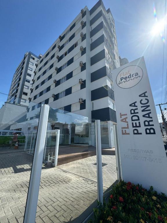 a building with a sign in front of it at Flat Pedra Branca Hotel in Palhoça