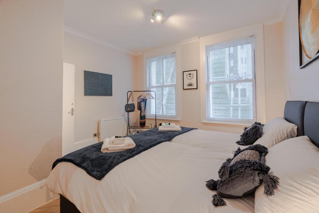two beds in a bedroom with white walls and windows at Central Brighton, 2 bedrooms, sleeps 5 in Brighton & Hove