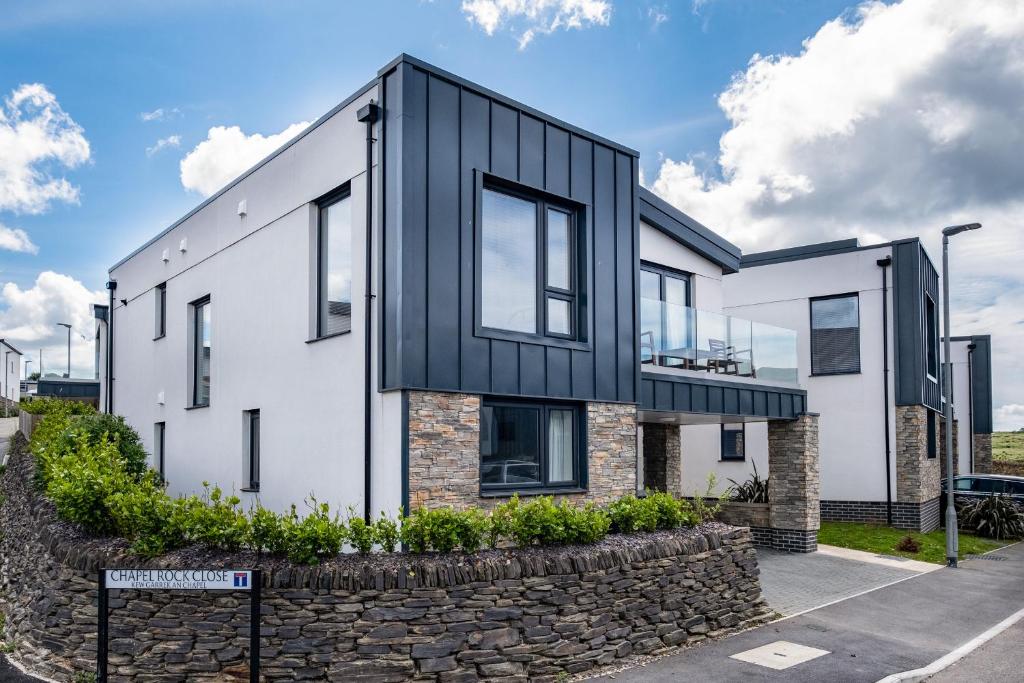 a house with a black facade and a stone wall at Beach Haven in Perranporth