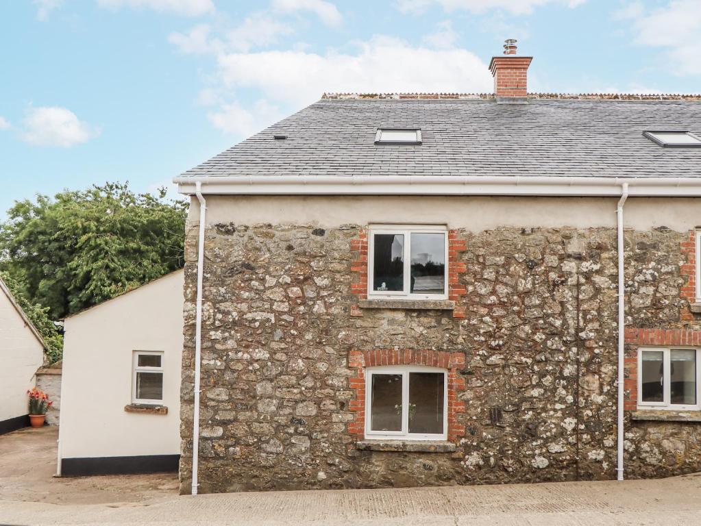 an old stone house with a stone wall at Aunty Junes Cottage in Okehampton
