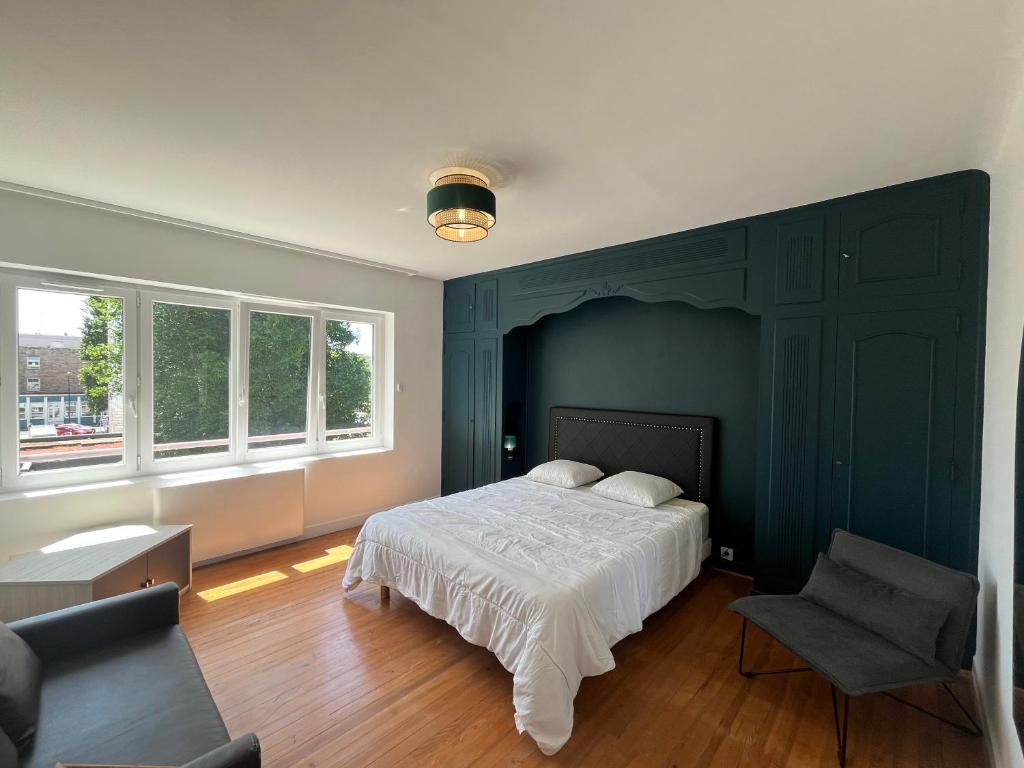 a bedroom with a bed and a chair and windows at Villa L'Etoile Du Littoral in Boulogne-sur-Mer